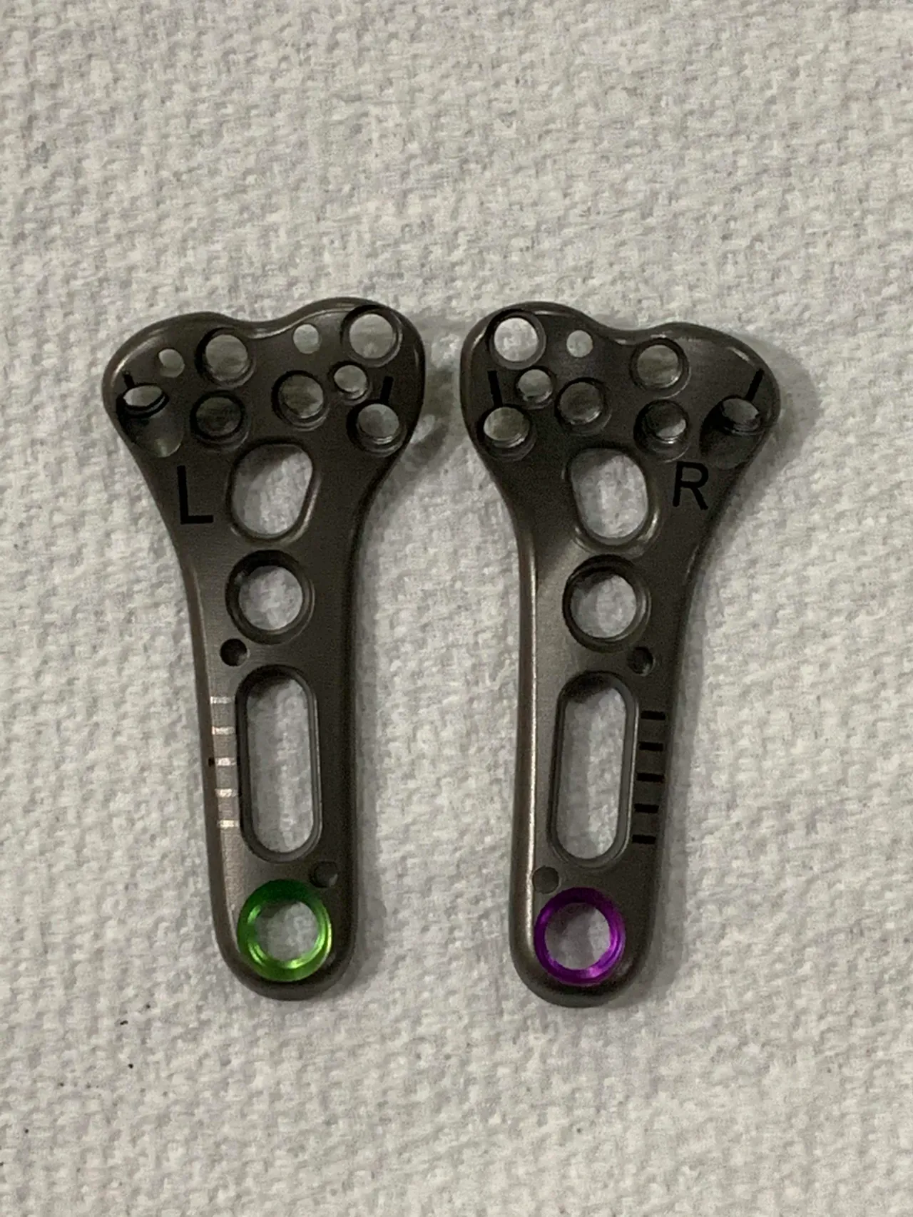 Left and right narrow plates side by side on a gray textured surface, marked L and R, one with a green ring and one with a purple ring at the shaft end.